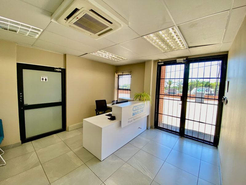 A bright and professional industrial reception area featuring tiled flooring, a suspended ceiling with integrated lighting, air conditioning, and secure access points.