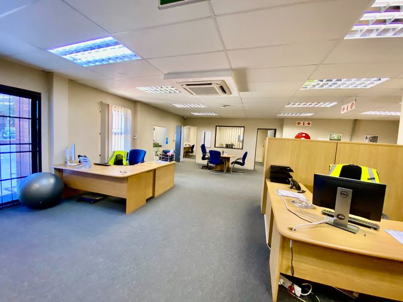 Open-plan industrial office space featuring suspended ceilings, recessed lighting, ducted air conditioning, and carpeted flooring with integrated partition walls.