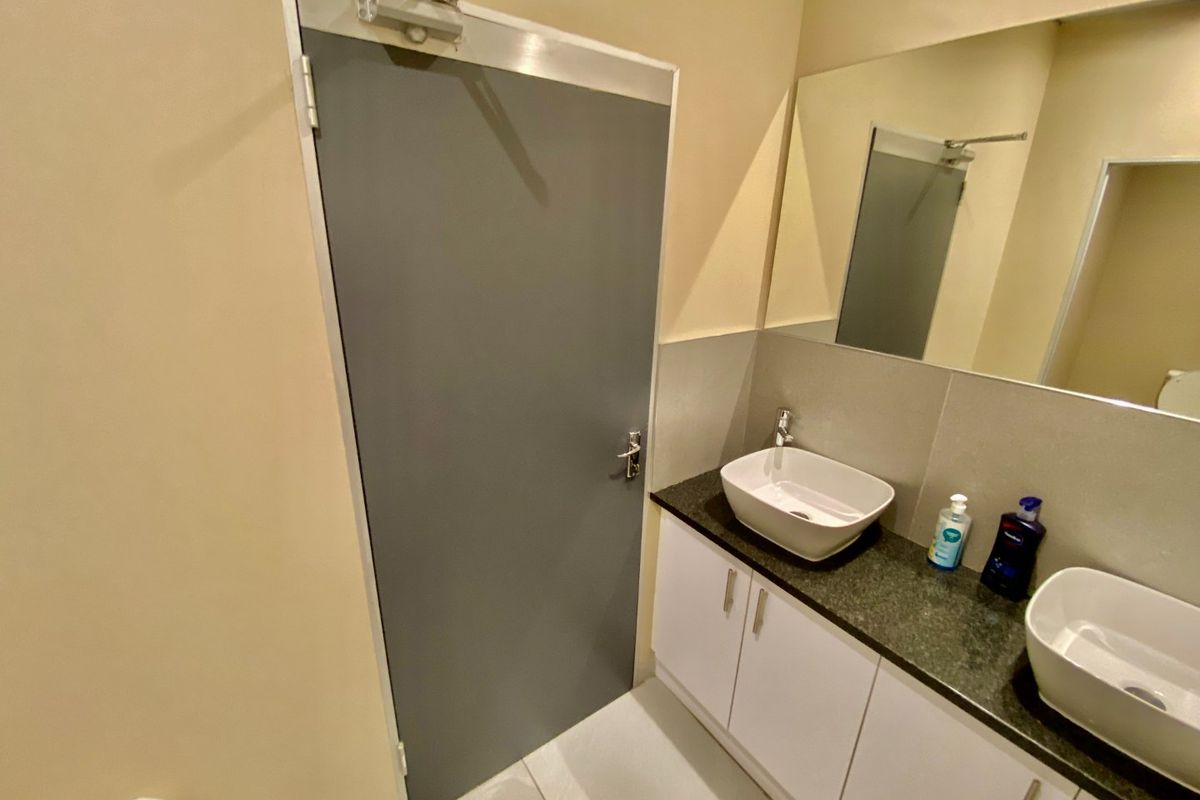 A modern industrial-style bathroom featuring a double vanity with vessel sinks, granite countertops, and clean white cabinetry.