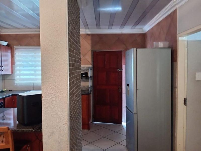 A functional kitchen area featuring tiled flooring, granite countertops, and built-in cabinetry, with a direct access door to the exterior.