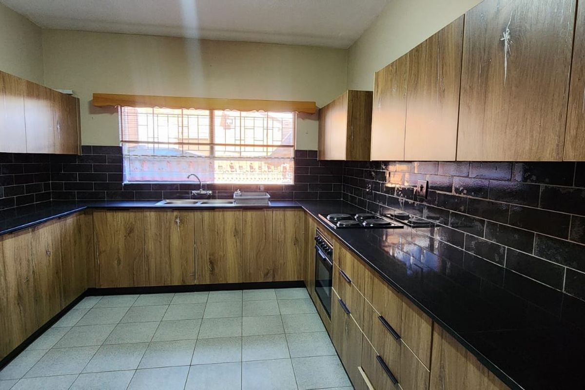 A functional kitchen featuring wood-look cabinetry, black subway tile backsplash, granite countertops, and built-in cooking appliances.