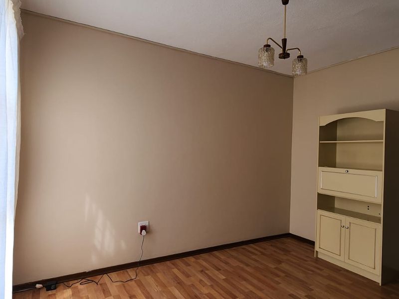 A clean, empty bedroom featuring laminate flooring, neutral wall tones, and a central ceiling light fixture, offering a versatile space for personalization.