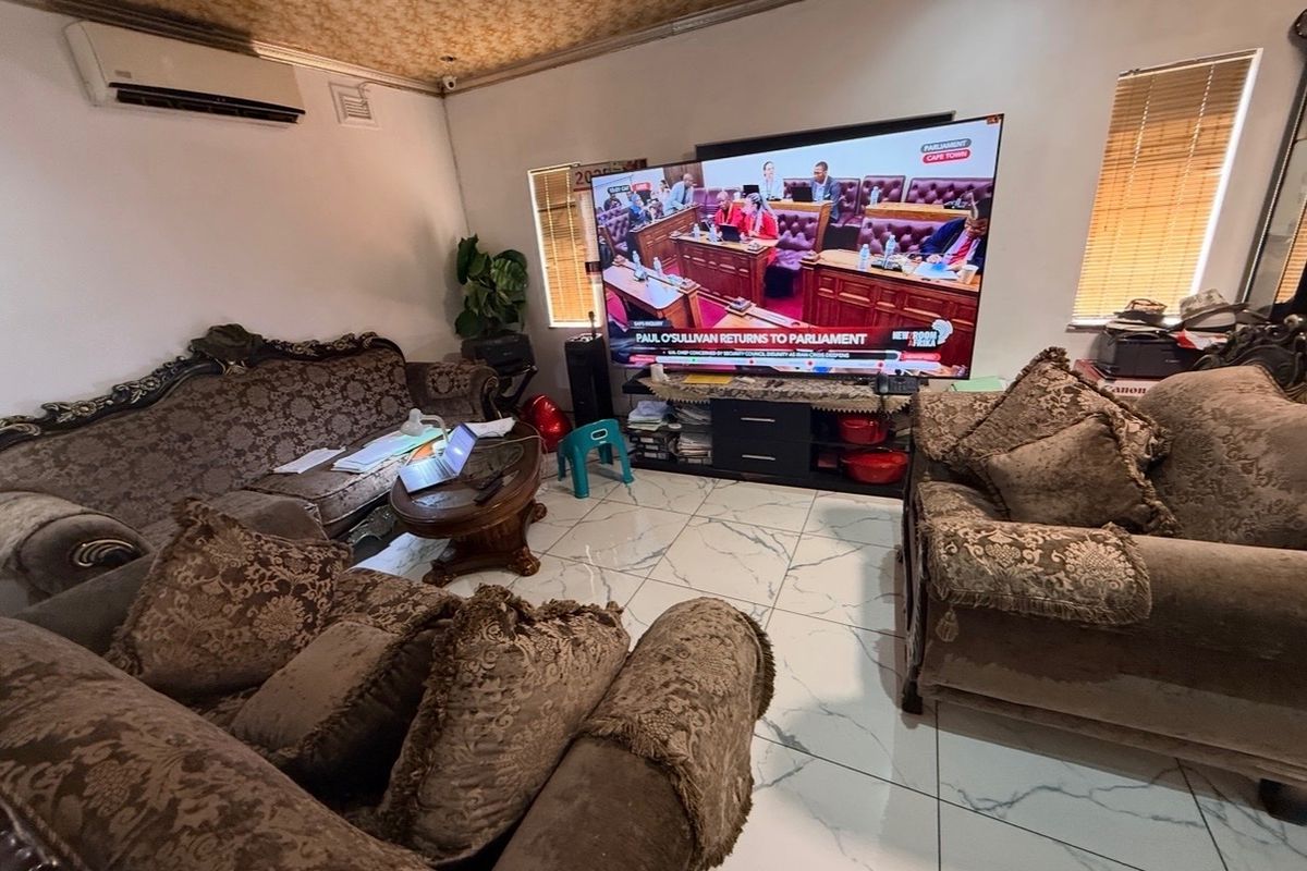 A living room featuring tiled flooring, a split-system air conditioner, and textured ceiling finishes, providing a functional space for relaxation.
