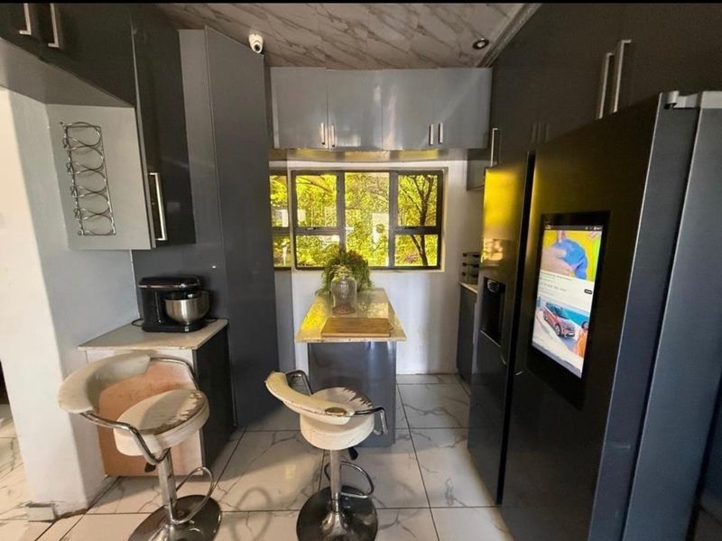 Compact kitchen featuring modern grey cabinetry, stone countertops, tiled flooring, and a window providing natural light.