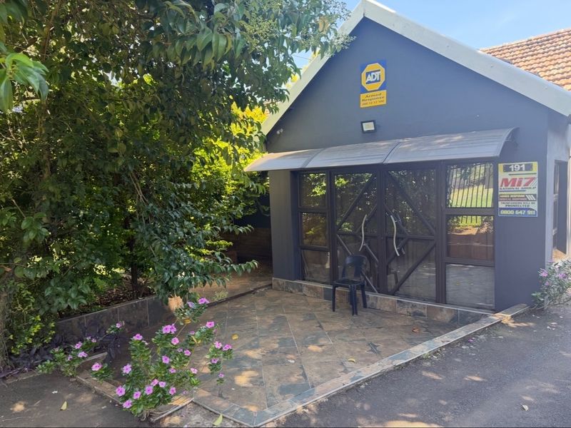 Front entrance area featuring a tiled patio, security gate, and protective awning, providing a secure and functional entry point to the property.