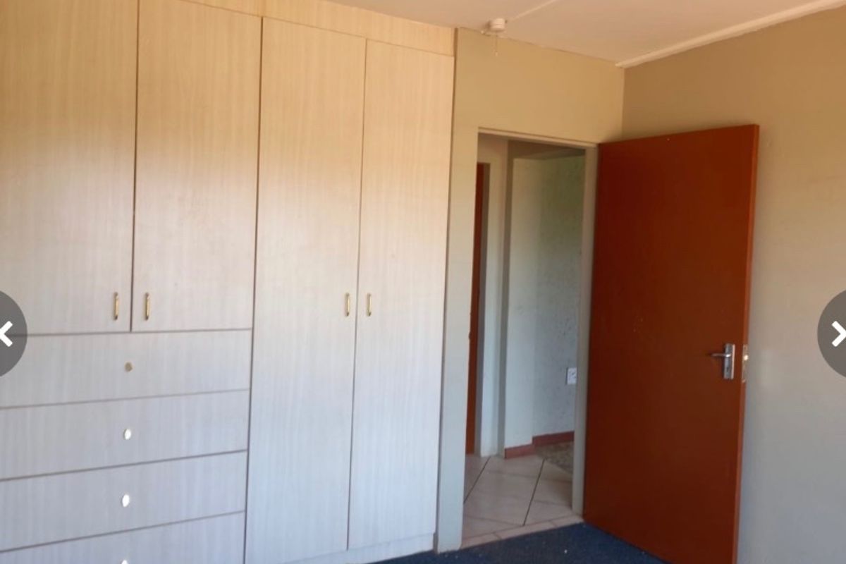 A bedroom featuring built-in wooden cupboards and a standard internal door, providing a clean and functional space.