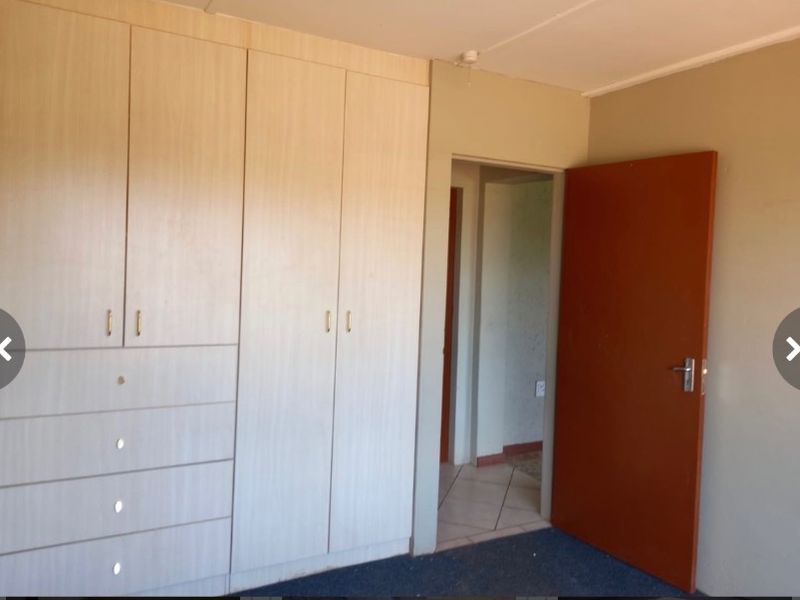 A bedroom featuring built-in wooden cupboards and a standard internal door, providing a clean and functional space.