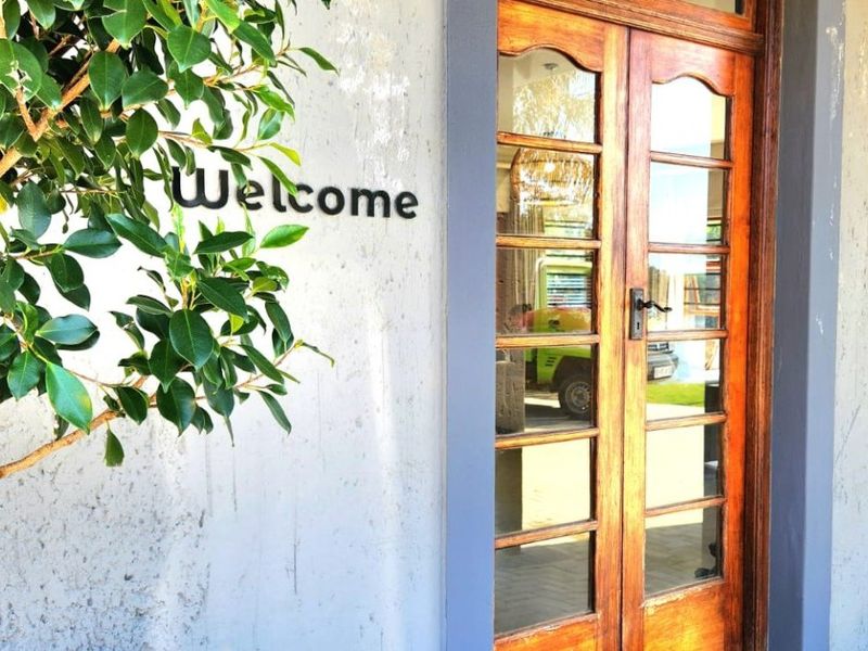 A close-up view of a wooden double entrance door with glass panels, set against a textured wall.