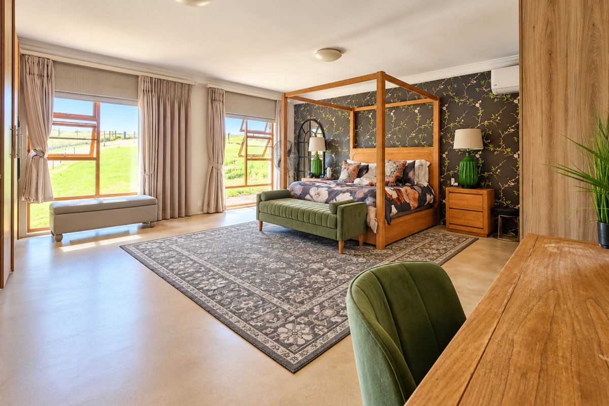 Spacious bedroom featuring polished concrete floors, built-in cabinetry, and large windows offering scenic rural views, creating a bright and well-maintained living space.