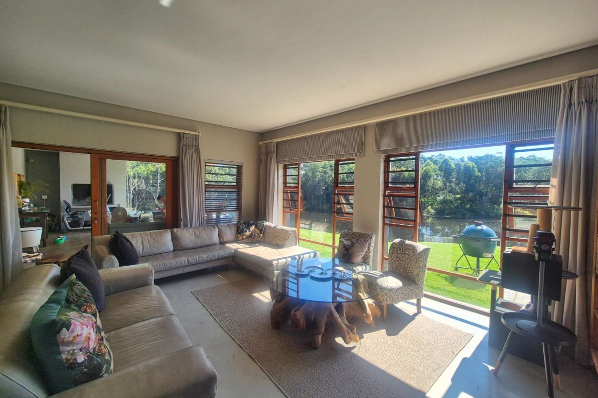 Spacious living room featuring polished concrete floors and expansive glass doors that provide seamless access to the garden and scenic water views.