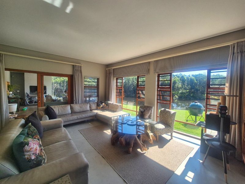 Spacious living room featuring polished concrete floors and expansive glass doors that provide seamless access to the garden and scenic water views.