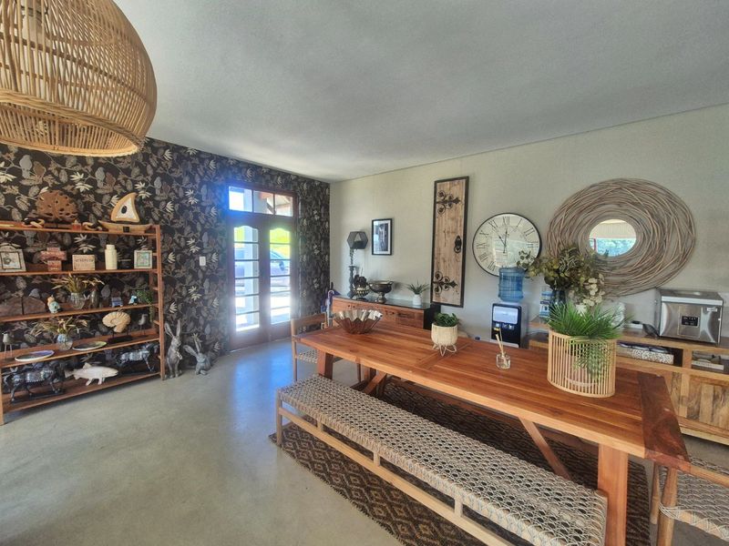 Spacious dining area featuring polished concrete floors, a striking feature wall, and direct access to the exterior through classic french doors.