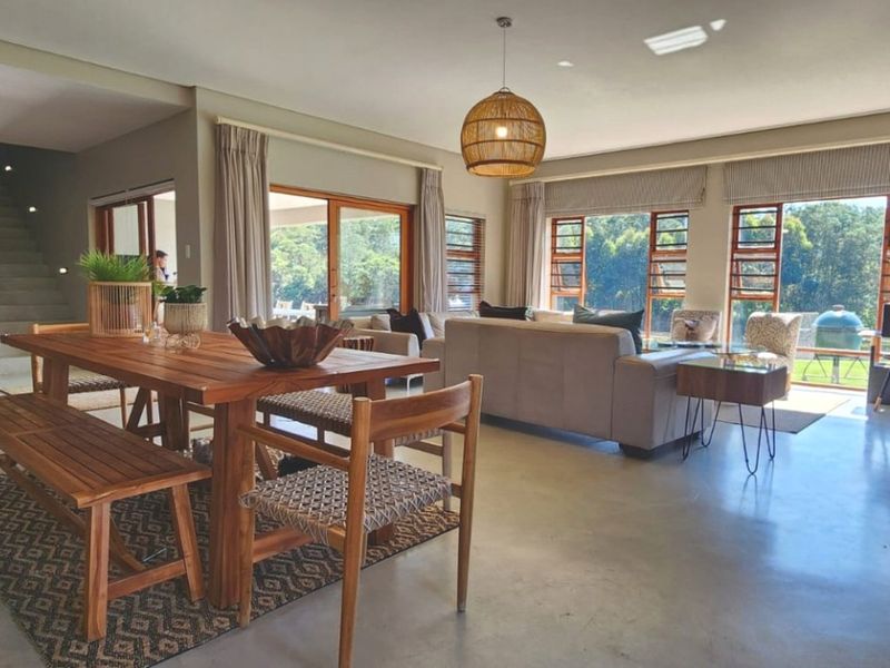 Spacious open-plan living and dining area featuring polished concrete floors, large sliding doors, and expansive windows with natural light and garden views.