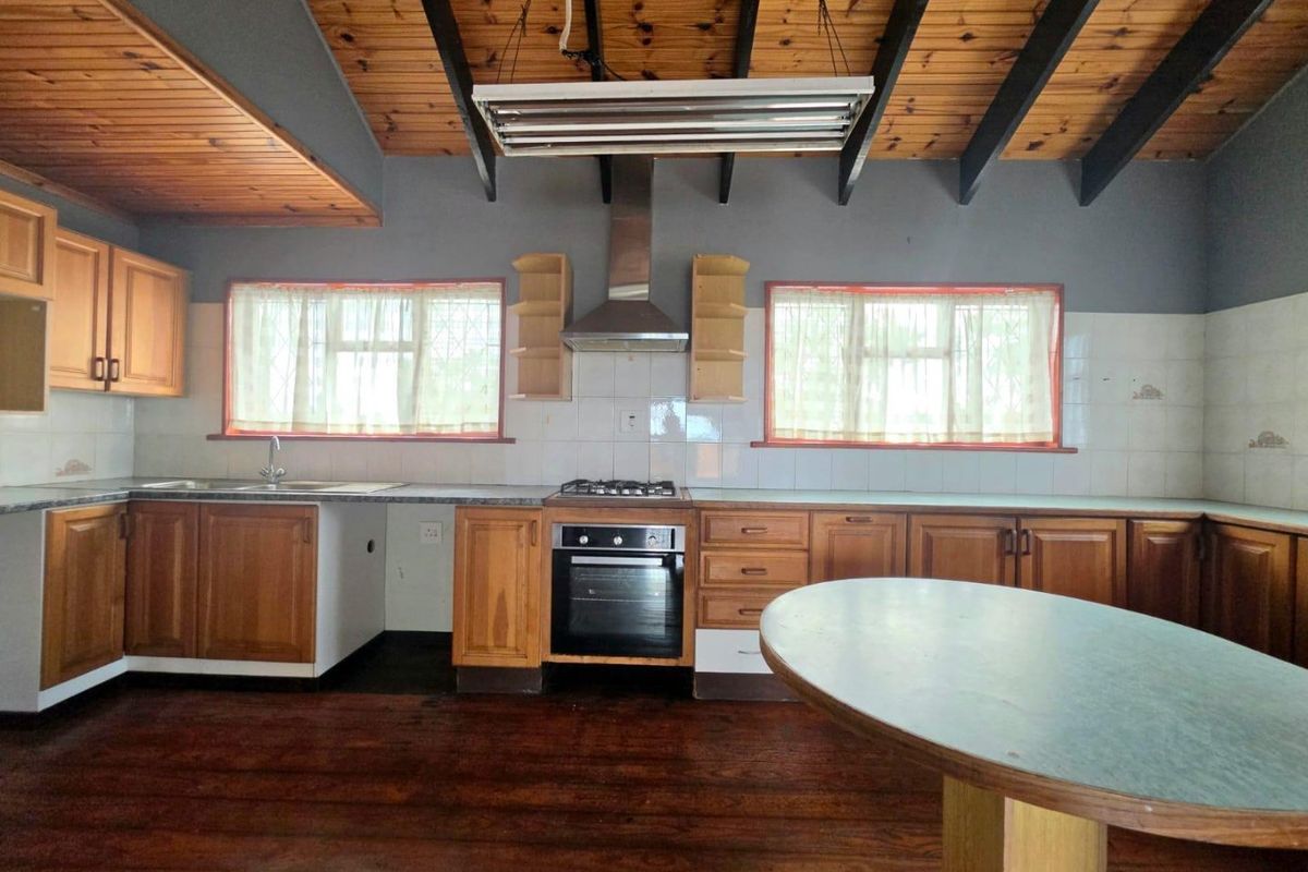 Spacious kitchen featuring wooden cabinetry, built-in oven, gas hob, and exposed timber ceiling beams, offering a functional layout with potential for modern updates.