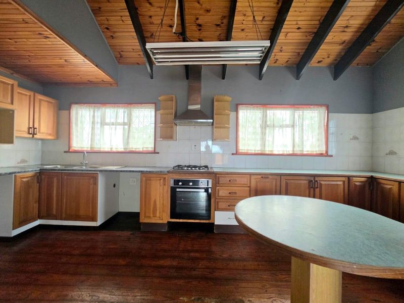 Spacious kitchen featuring wooden cabinetry, built-in oven, gas hob, and exposed timber ceiling beams, offering a functional layout with potential for modern updates.