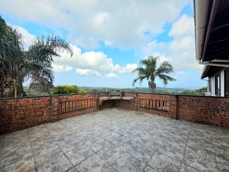Spacious outdoor patio featuring a brick balustrade, built-in braai area, and expansive elevated views.