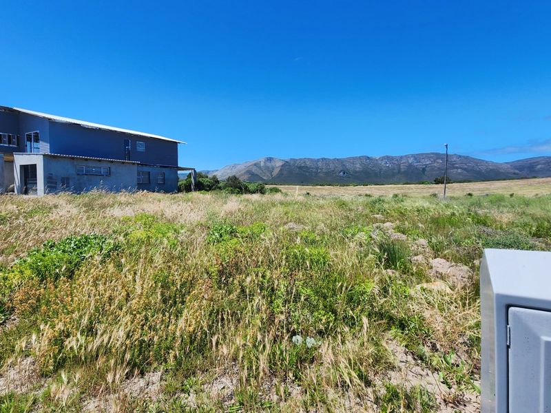 A vacant residential plot featuring a partially constructed building with scenic mountain views and natural vegetation.
