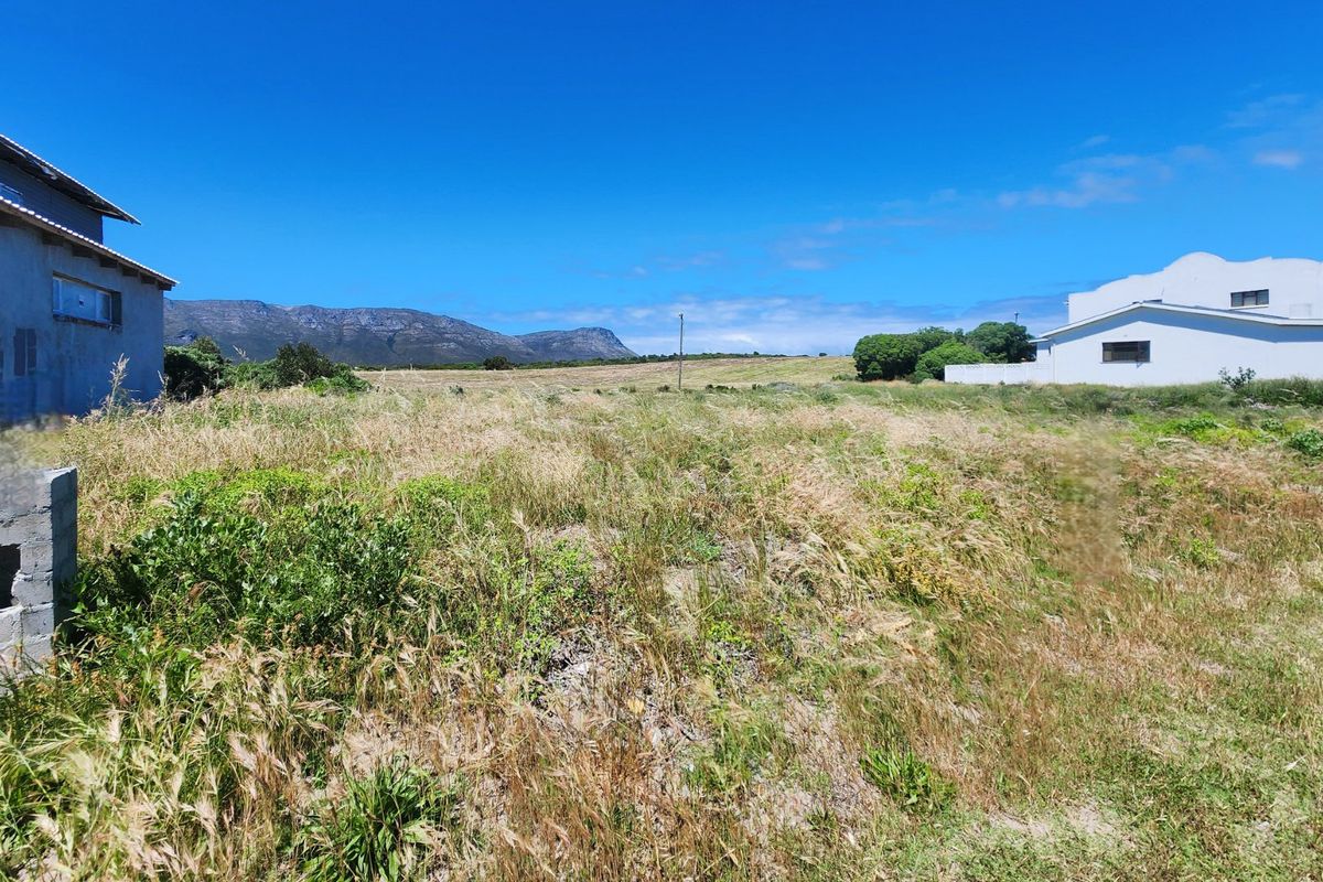 A view of a vacant residential plot featuring natural vegetation and scenic mountain views in the background.