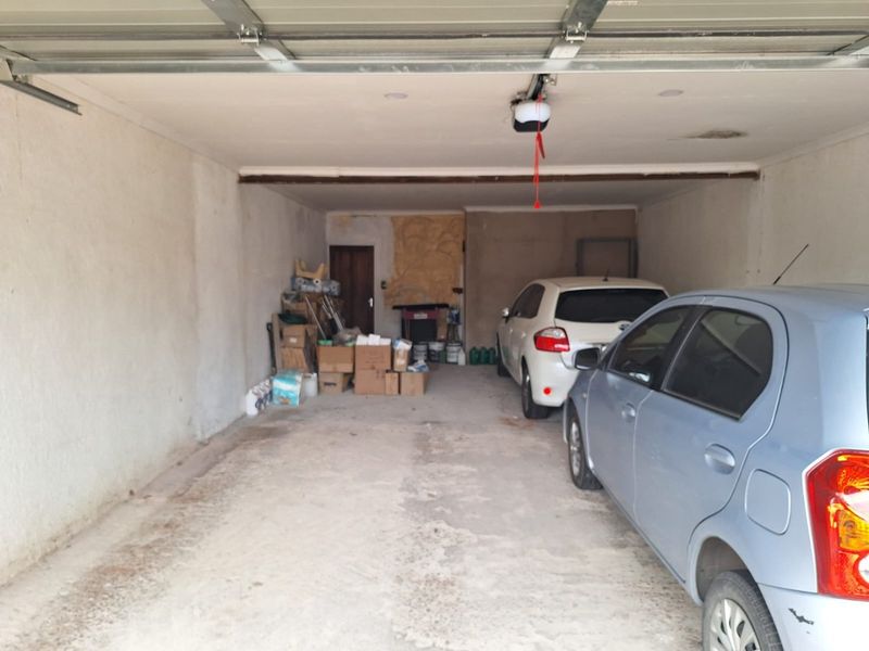 A functional double garage featuring concrete flooring and an automated door mechanism, providing secure parking and additional storage space.