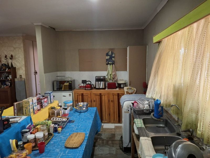 A functional kitchen featuring wooden cabinetry, a double bowl sink, and tiled splashbacks, offering potential for modernization and layout optimization.