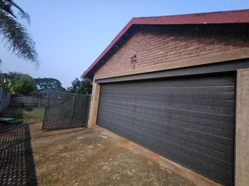 Exterior view of a detached garage featuring a dark sectional door, brick facade, and concrete driveway access.