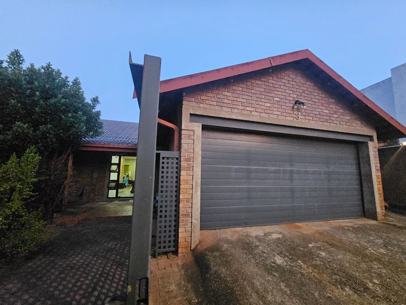 Front elevation of a brick house featuring a single sectional garage door, paved driveway, and a gabled roof structure.