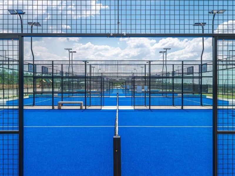 A well-maintained professional padel court facility featuring high-quality synthetic turf, secure wire mesh fencing, and integrated floodlighting for evening play.
