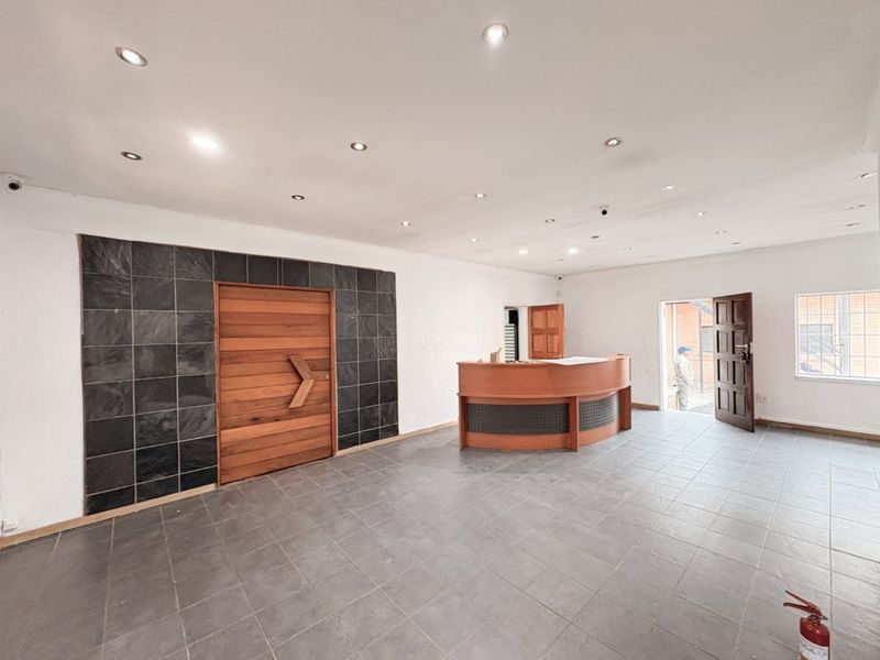 Spacious commercial entry area featuring a built-in reception desk, slate tile feature wall, recessed lighting, and durable tiled flooring.