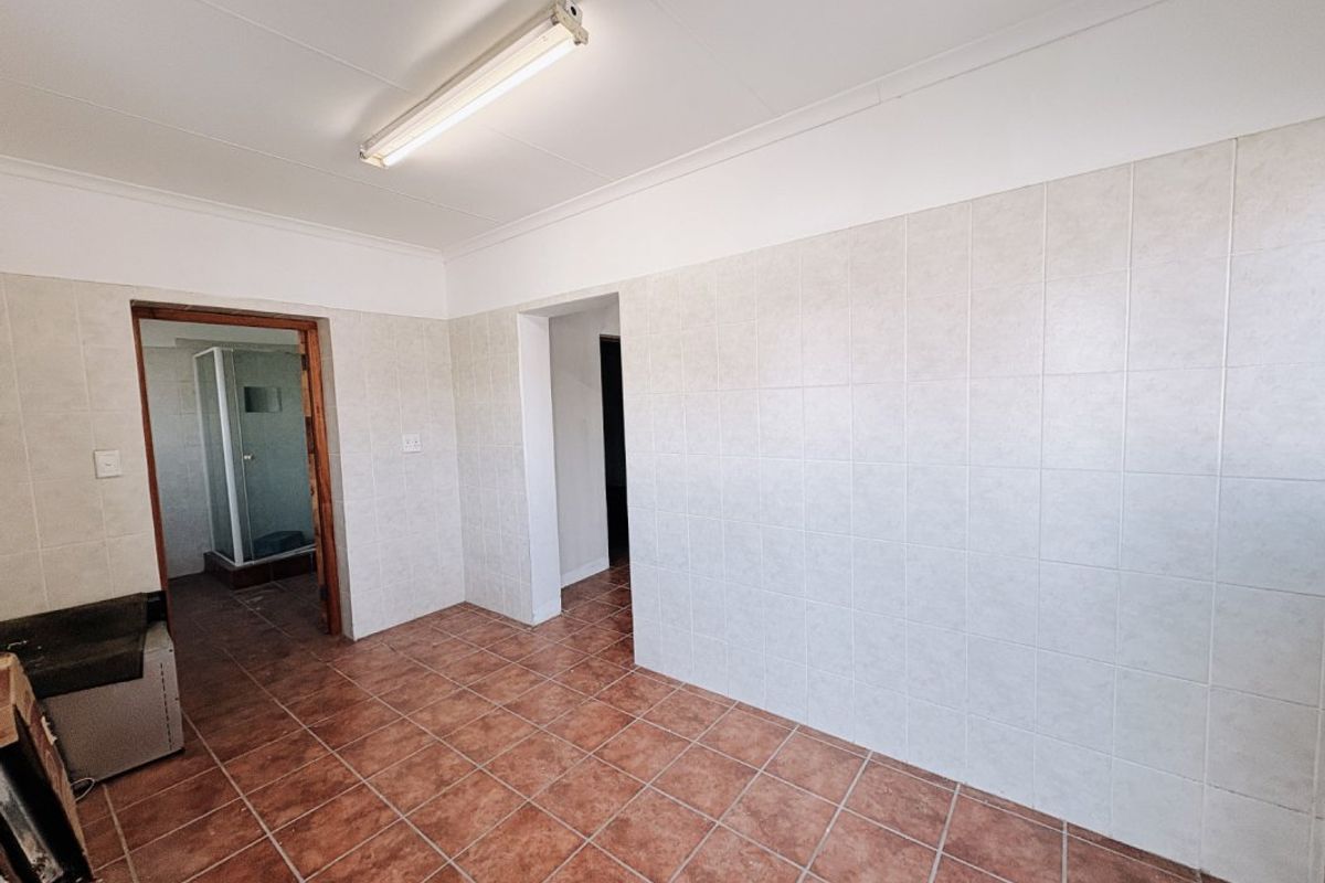 A functional bathroom space featuring tiled walls and flooring, with a separate shower cubicle visible through the doorway.