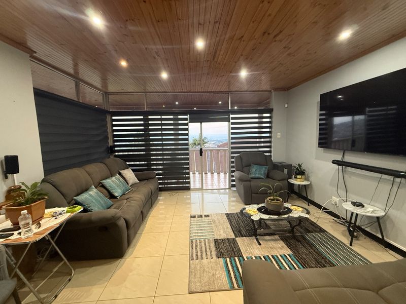 Spacious living room featuring a warm timber ceiling, recessed lighting, and large sliding glass doors that open to a balcony with scenic views.
