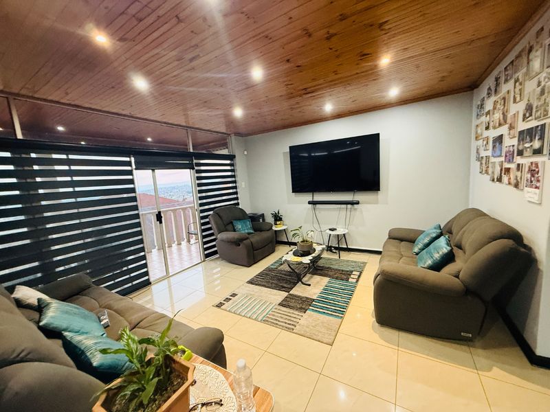 Spacious living room featuring a warm timber ceiling, recessed lighting, large format floor tiles, and sliding glass doors leading to an outdoor balcony area.