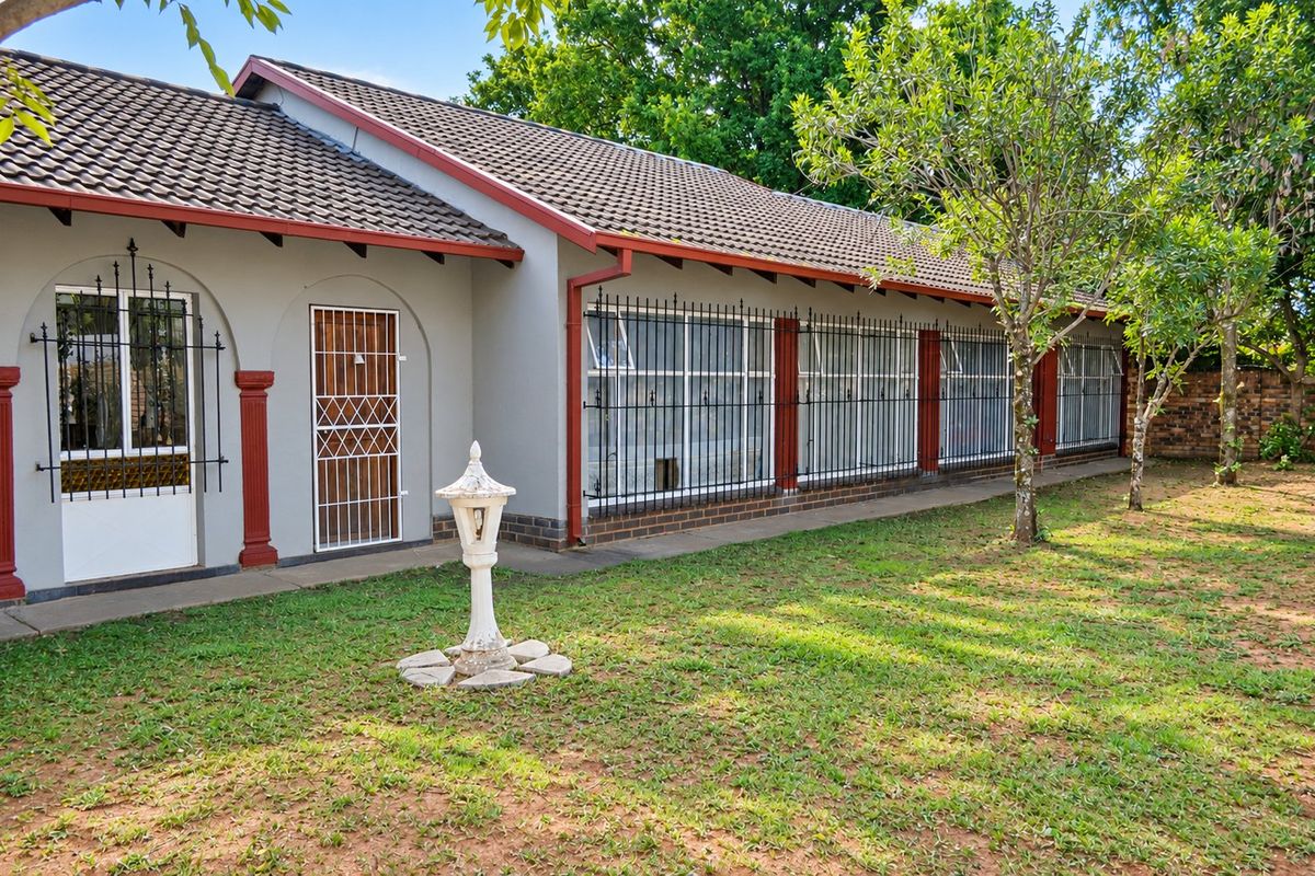 Rear view of the house featuring a tiled roof, security bars on windows, and a paved walkway leading along the exterior wall.