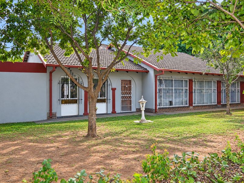 Rear view of the house featuring a tiled roof, security bars on windows, and a garden area with a concrete pathway.