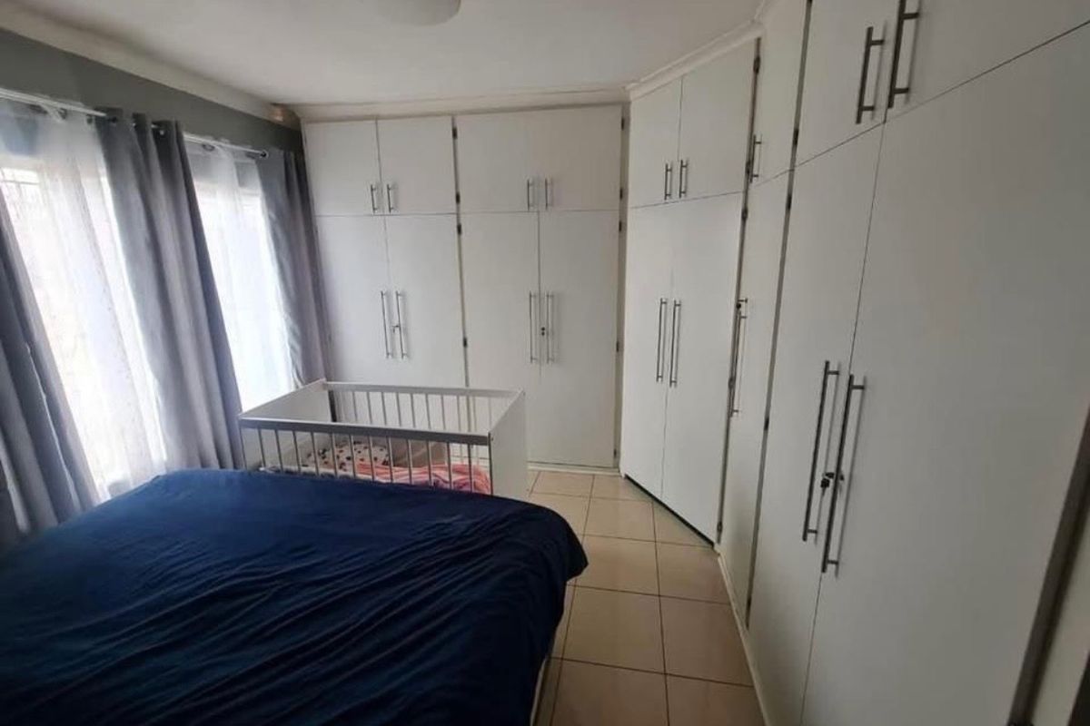 Bedroom featuring extensive white built-in cupboards and tiled flooring, providing ample storage space.