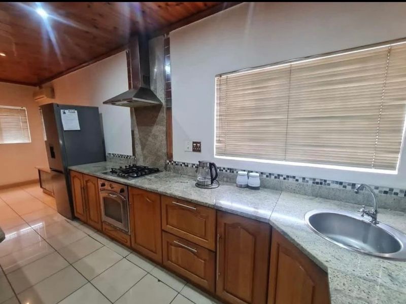 Kitchen featuring granite countertops, timber ceiling, built-in oven, gas hob, and stainless steel sink with tiled flooring.