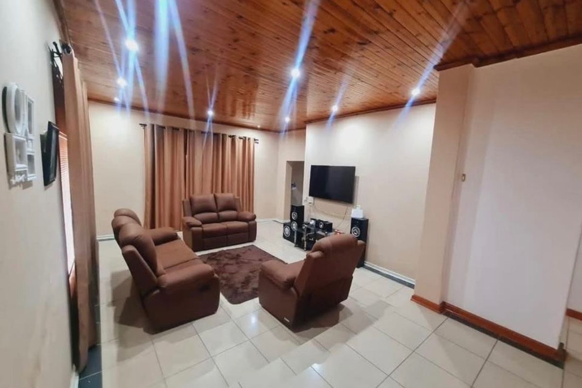 Spacious living room featuring a warm timber tongue and groove ceiling, recessed downlighting, and neutral tiled flooring.
