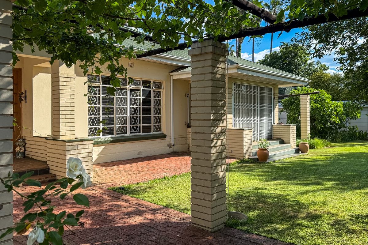 A well-maintained rear exterior featuring a brick patio, pergola, and established garden, providing a pleasant outdoor living space.