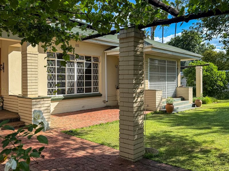 A well-maintained rear exterior featuring a brick patio, pergola, and established garden, providing a pleasant outdoor living space.