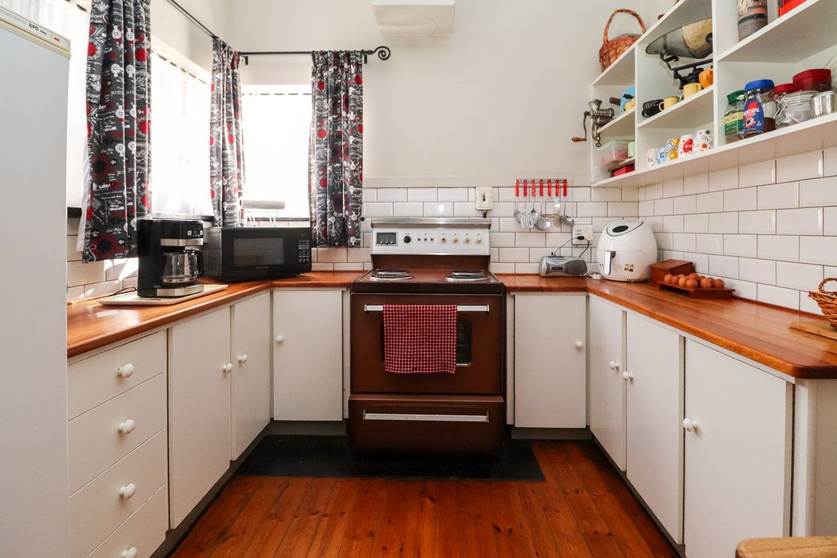 A functional kitchen featuring white cabinetry, wooden countertops, subway tile backsplash, and timber flooring, providing a classic and practical workspace.