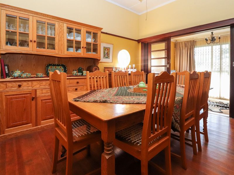 A traditional dining room featuring warm hardwood flooring, built-in wooden cabinetry, and sliding doors leading to an adjacent living space.