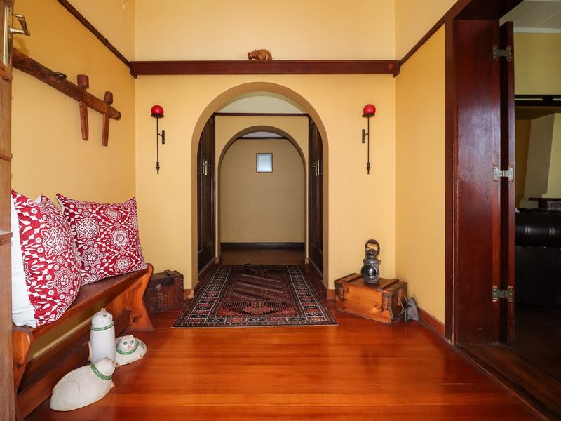 A warm and inviting hallway featuring polished hardwood flooring and distinctive arched doorways that lead into the home's living spaces.