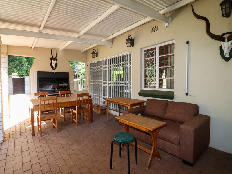 Covered outdoor patio featuring brick paving, a built-in braai, and direct access to the home through a security gate.