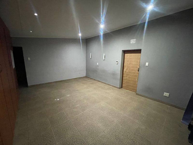 An empty bedroom featuring tiled flooring, recessed downlights, and built-in cupboards, offering a neutral canvas for personalization.