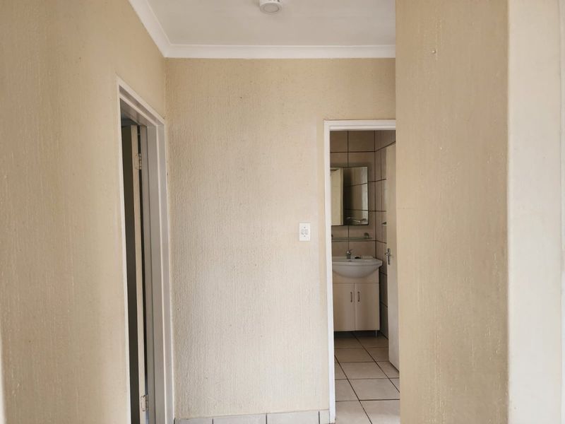 A view through a hallway leading into a bathroom featuring a vanity cabinet and tiled flooring.