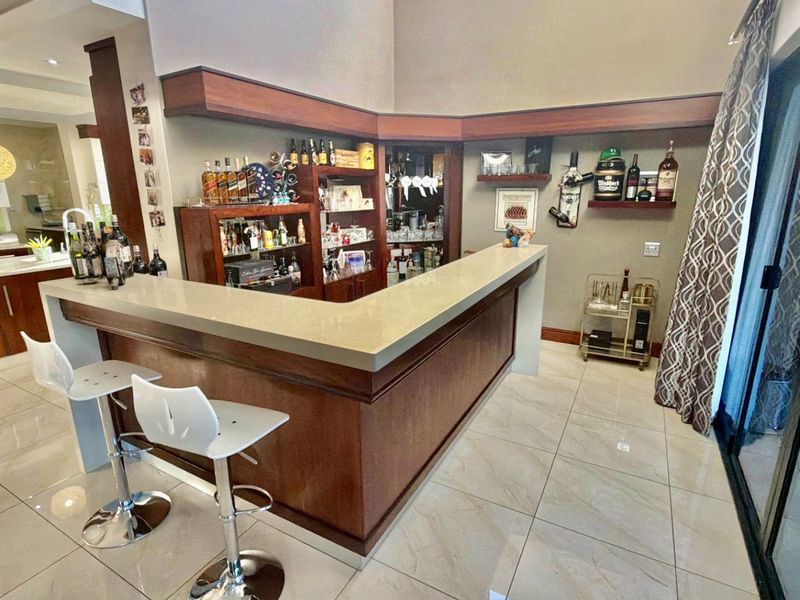 A well-appointed home bar area featuring a built-in wooden counter with stone top, integrated cabinetry, and direct access to the patio through sliding doors.
