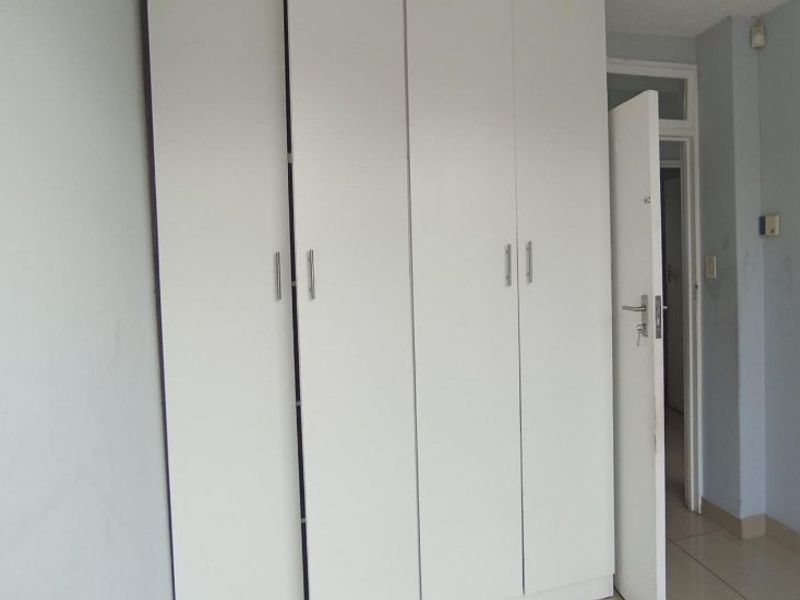 A bedroom featuring built-in cupboards and tiled flooring, presenting a functional space ready for personalization.