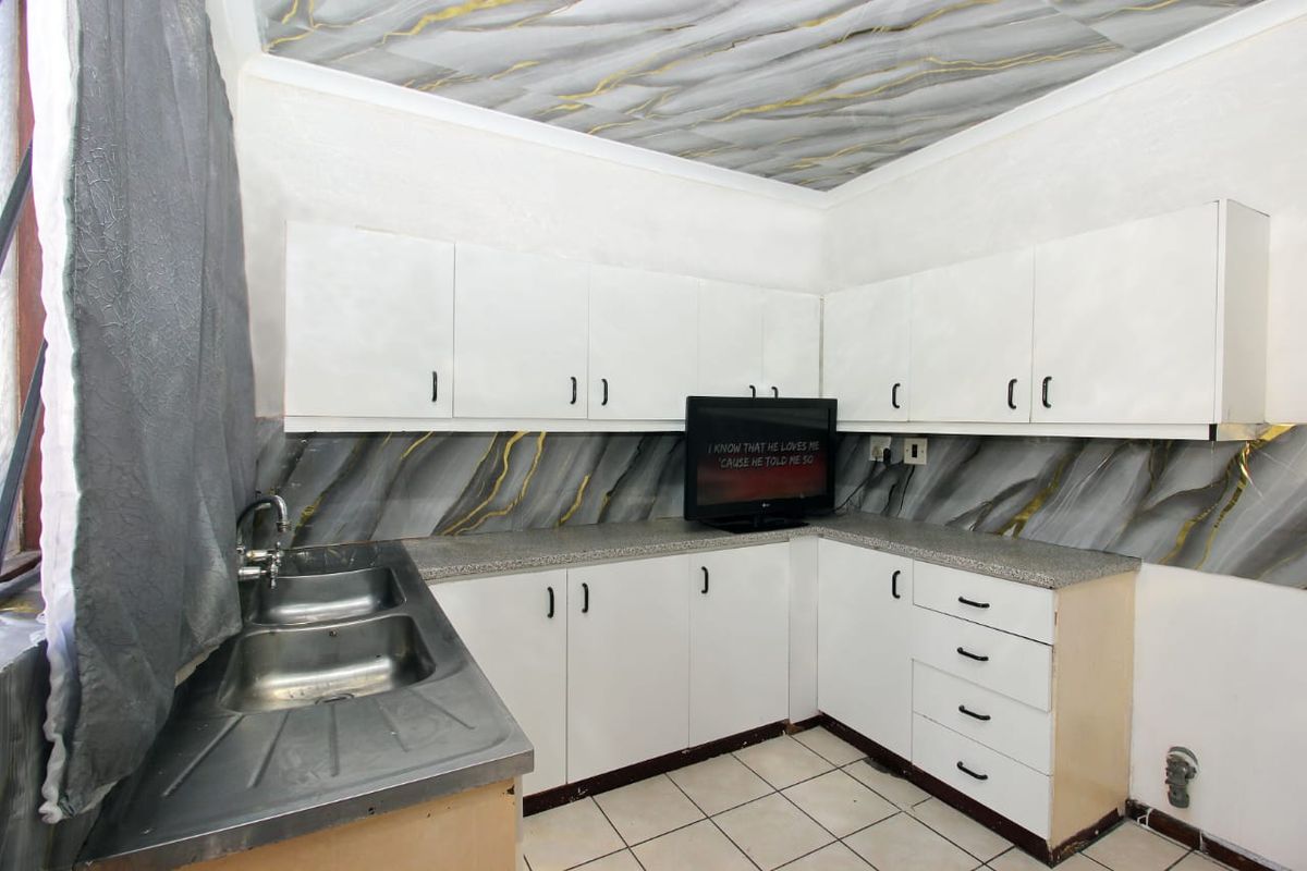 Kitchen featuring white cabinetry, laminate countertops, double bowl stainless steel sink, and tiled flooring with a decorative ceiling finish.