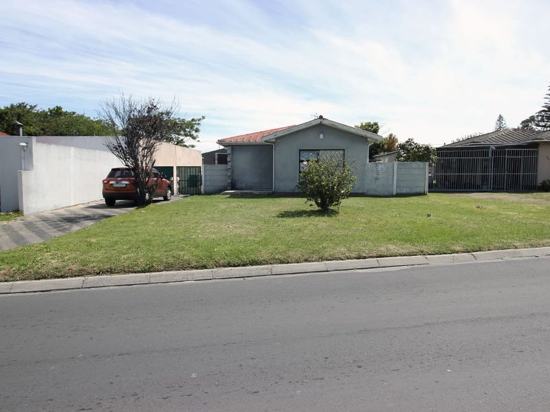 Front view of a single-story house featuring a tiled roof, paved driveway, and concrete boundary walling.