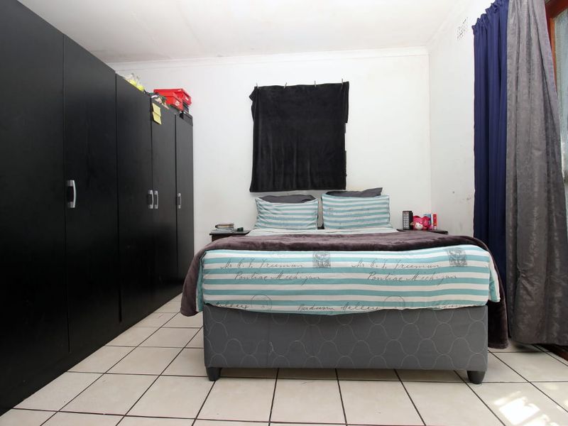 A bedroom featuring tiled flooring, built-in cupboards, and a sliding door providing access to the exterior.