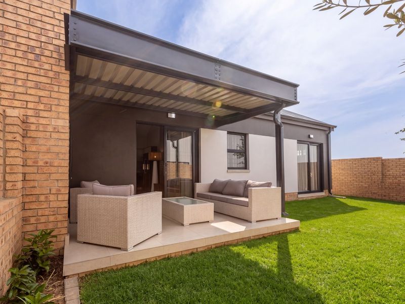 A well-maintained covered patio featuring a modern steel beam pergola, tiled flooring, and direct access to the rear garden through sliding glass doors.